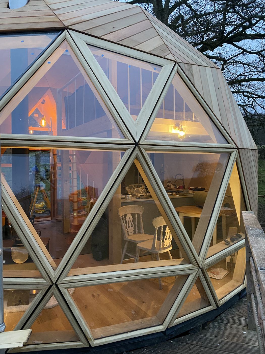 Warm light through the glazed front of The Fold dome at dusk