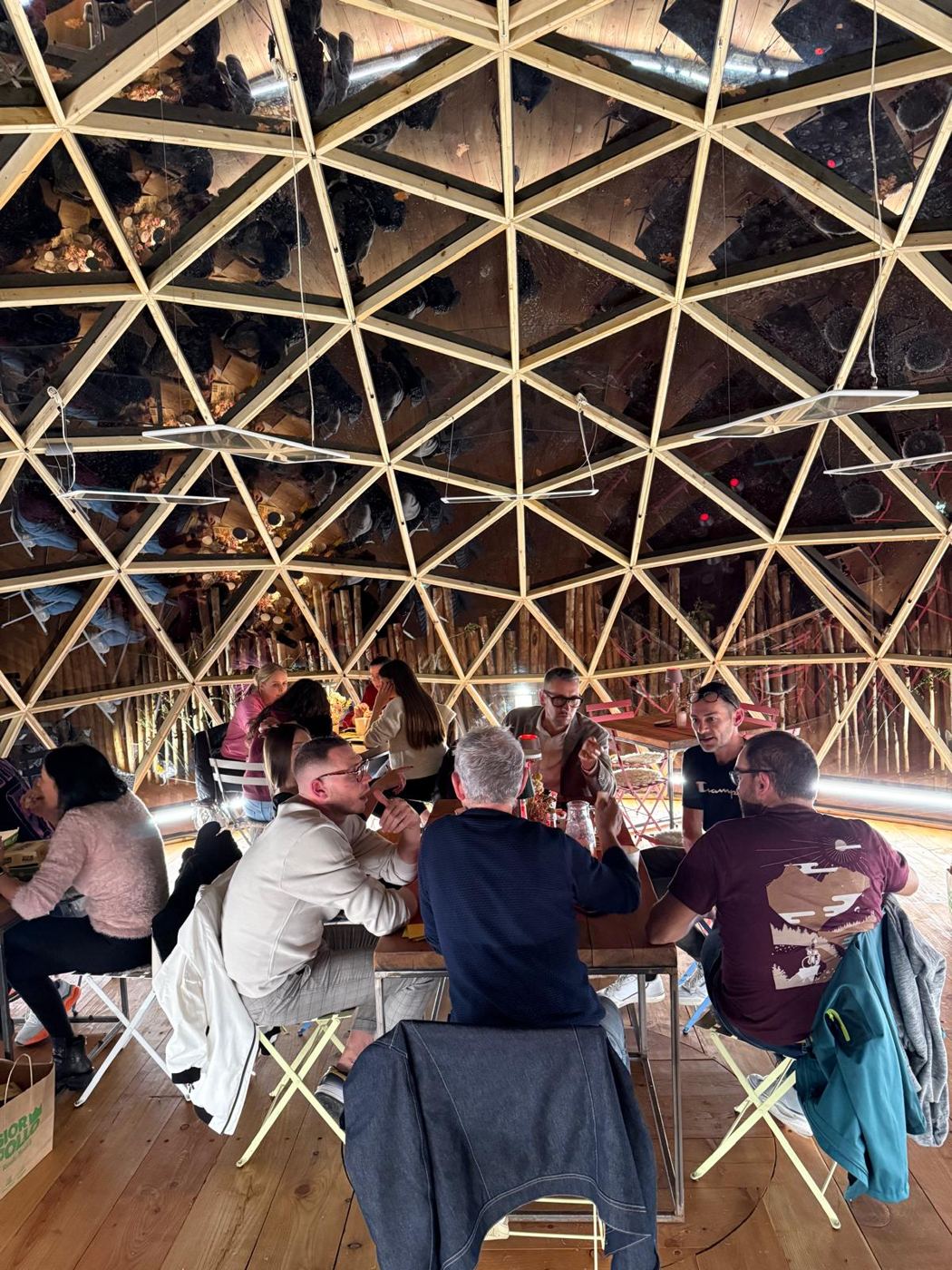 Guests dining inside the dome beneath the timber geodesic lattice